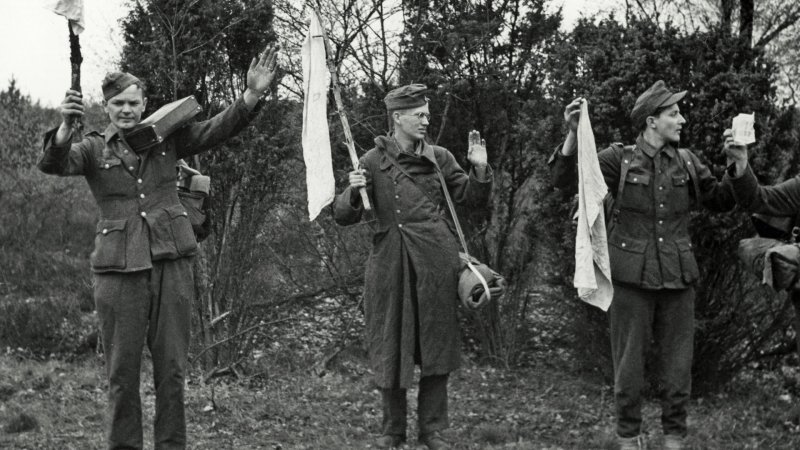 Wehrmachtssoldaten ergeben sich 1945 und halten weiße Tücher hoch.