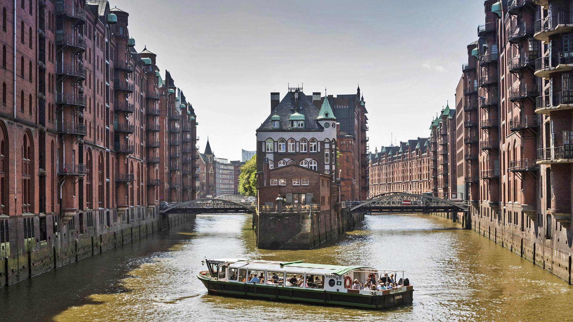 Blick auf das Wasserschloss in der Speicherstadt, davor eine Barkasse.