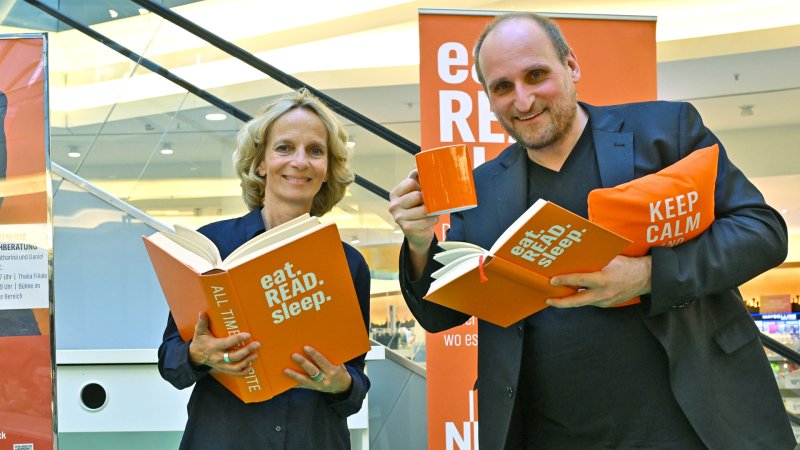 Katharina und Daniel stehen nebeneinander mit Büchern in den Händen.