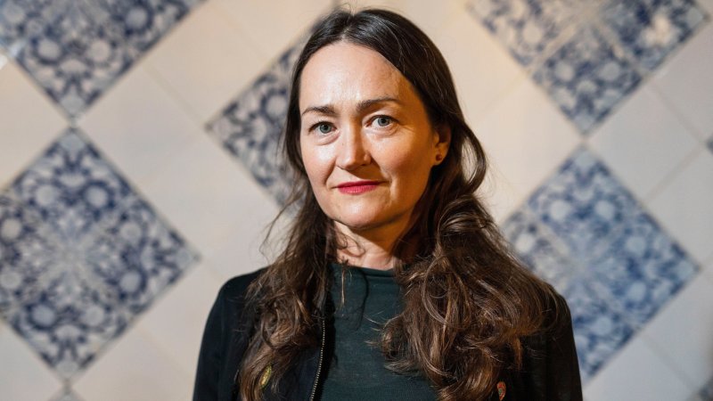 Eine Frau mit langen braunen Haaren blickt in die Kamera.