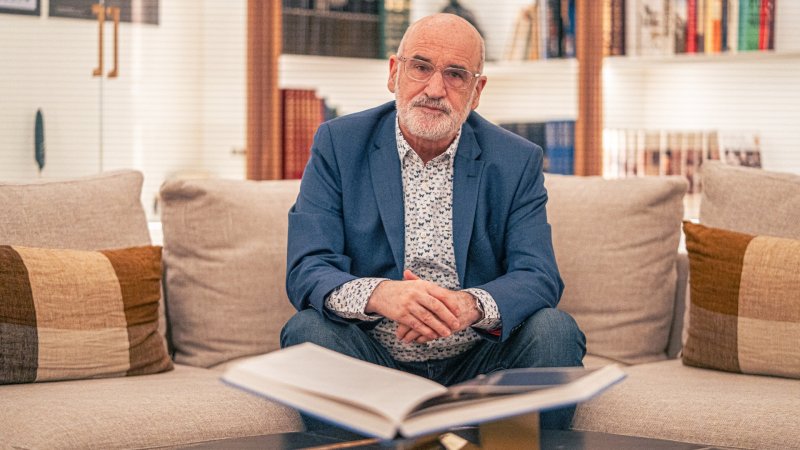 Fernando Aramburu sitzt mit Hemd und blauem Sakko auf einem Sofa.