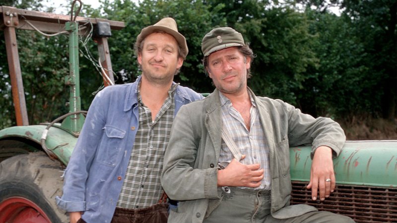 Neues aus Büttenwarder: Die Bauern Adsche und Brakelmann lehnen an einem Trecker.