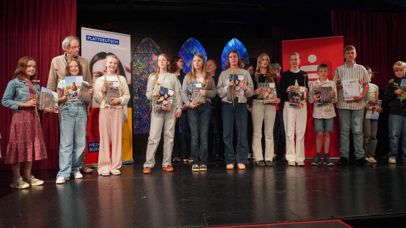 Viele Schülerinnen und Schüler stehen auf einer Bühne.