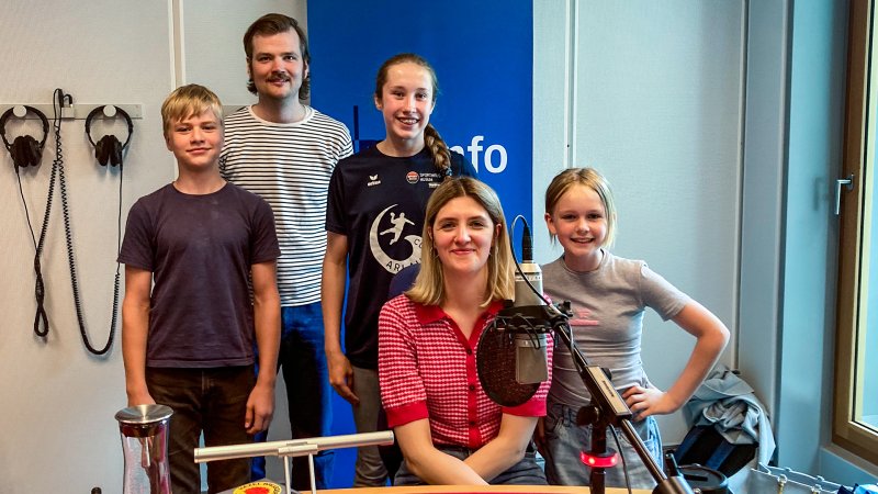Im Studio des NDR sitzen drei Kinder mit einer Frau und einem Mann.