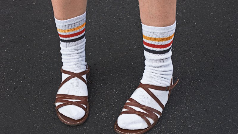 Jemand steht mit Socken und Sandalen auf der Straße.