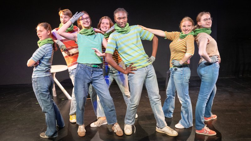 Jugendliche stehen auf einer Bühne und lächeln in die Kamera.