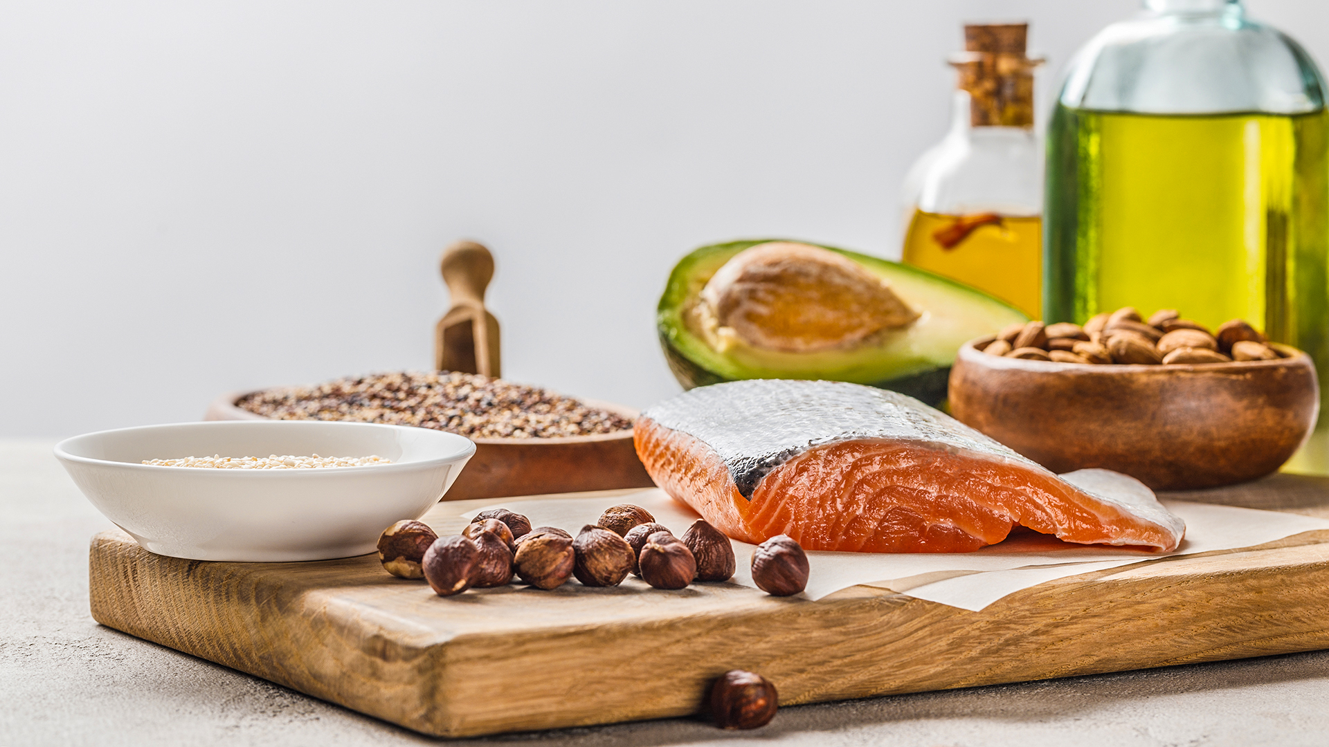 Avocado, Lachs, Nüsse und Öle auf einem Holzbrett