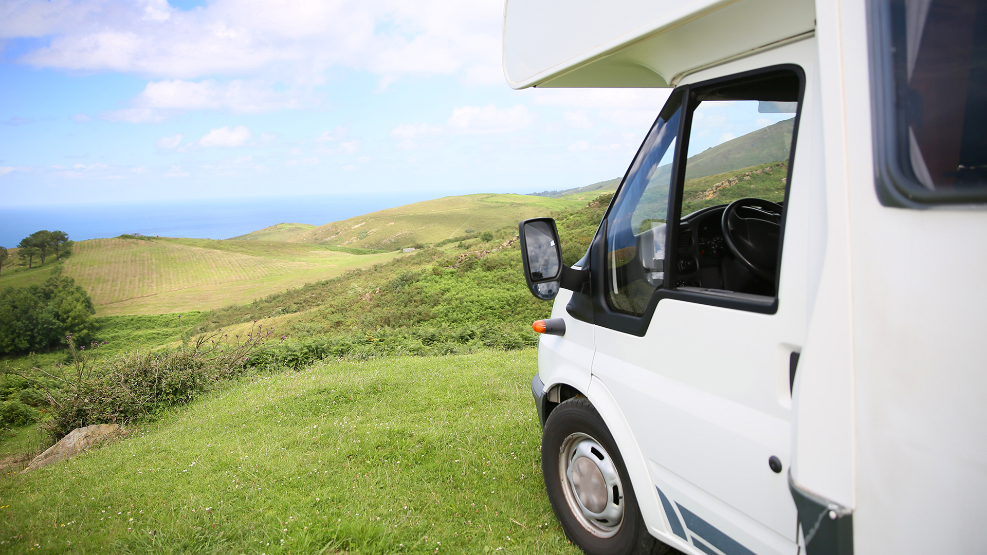 Ein Wohnmobil steht auf einer hügeligen Gras-Landschaft.