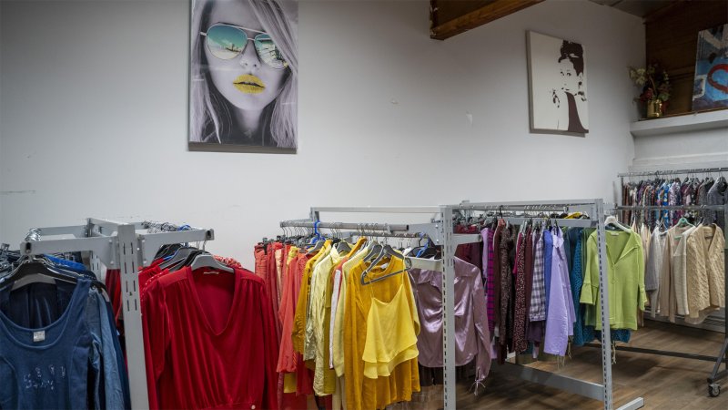 Secondhand-Kleidung hängt nach Farben sortiert in einem Geschäft.