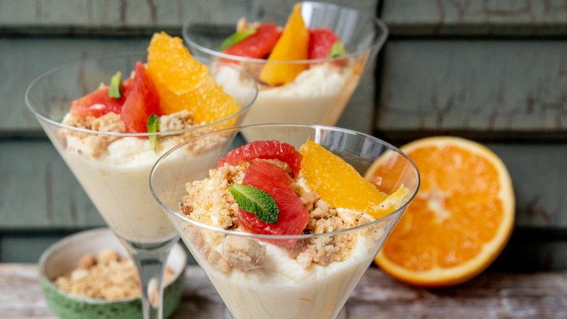 Weiße Schokoladen-Mousse mit Zitrusfrüchten und Crunch in Gläsern serviert.