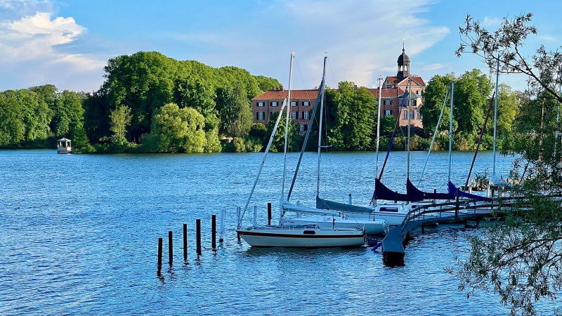 Segelboote liegen auf dem Eutiner See vor dem Schloss.