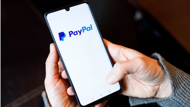 Auf dem Display eines Handys ist das Logo des Online-Bezahldienstes Paypal abgebildet
