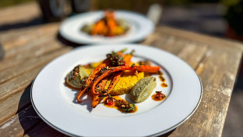 Gegrillte Karotten mit Auberginencreme, Chimichurri und Couscous auf einem weißen Teller