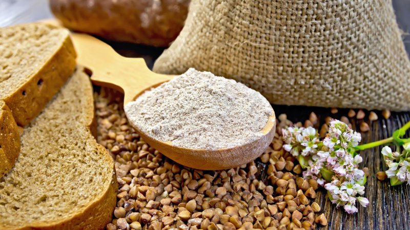 Buchweizen-Körner, Brot und gemahlener Buchweizen auf einem Holzlöffel.